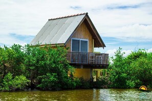 A wooden house with a metal roof, a balcony, and surrounded by dense greenery. - Sands Kalpitiya By GLN (Kalpitiya)