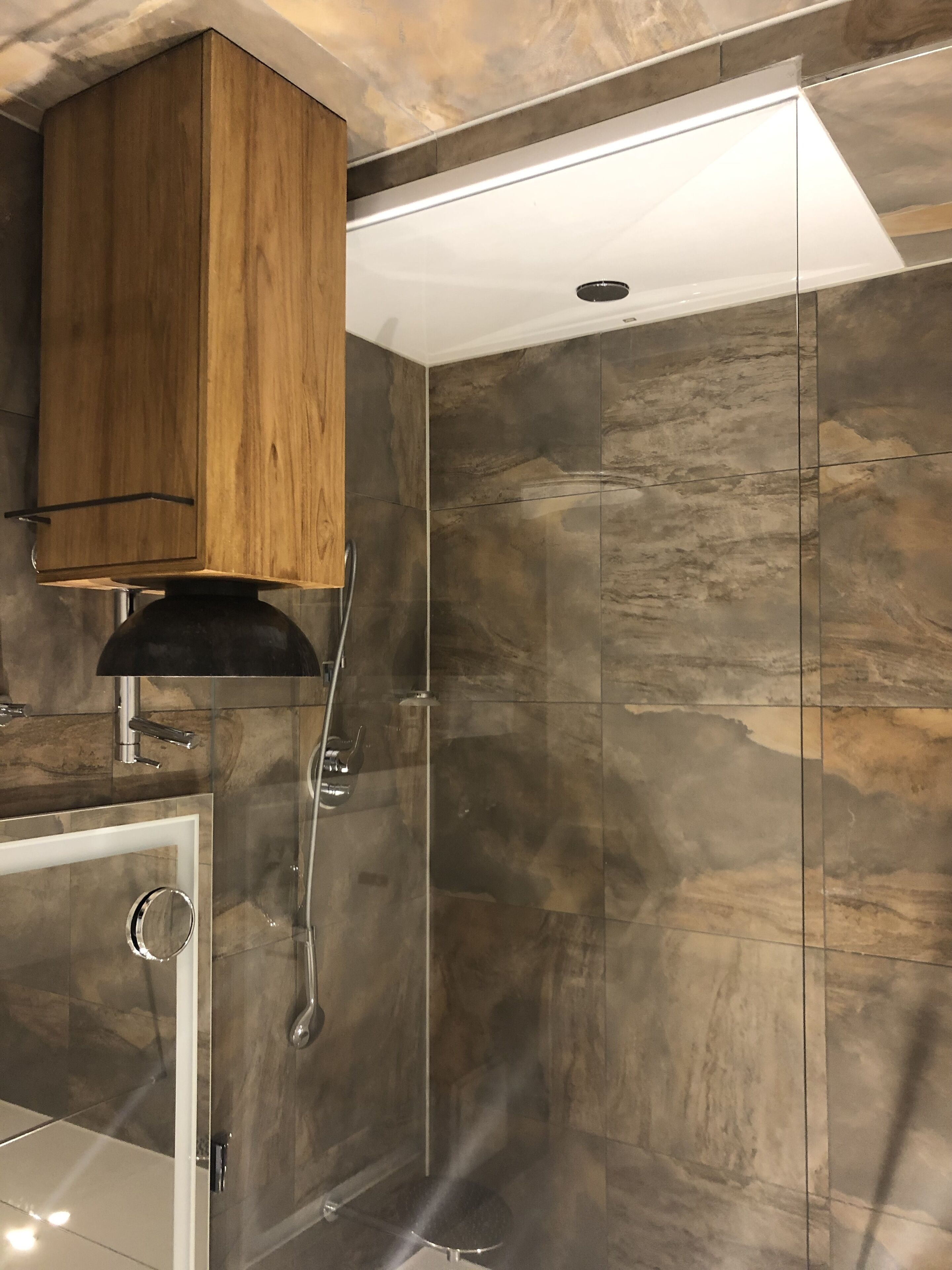 A modern bathroom with a wooden cabinet, a glass shower enclosure, and a white ceiling.