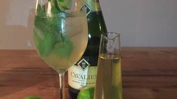 Una ampolla de cava CAVALIER, un got amb una taronja i un altre got de cava sobre una taula de fusta.