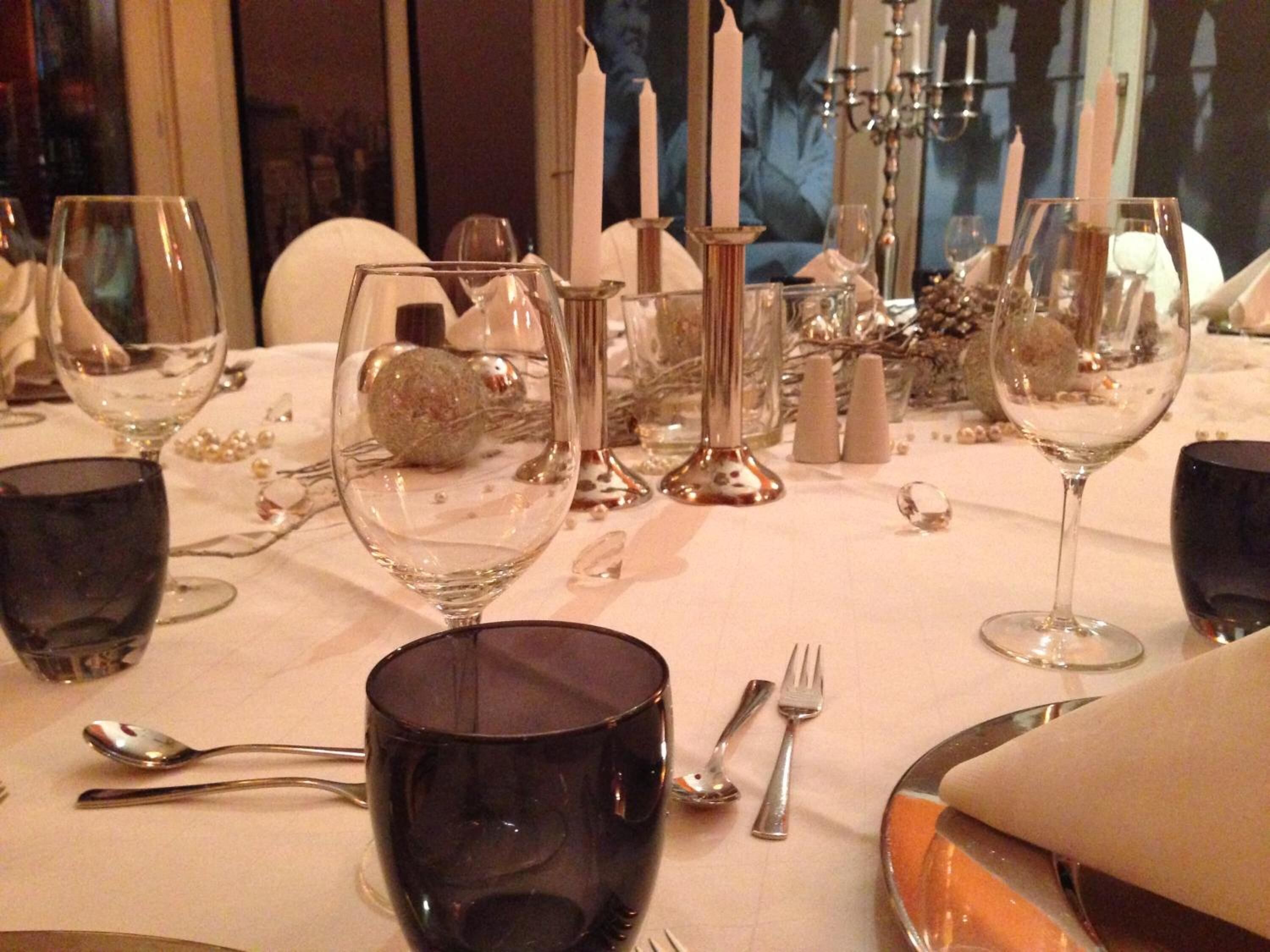A dining table set with wine glasses, a dark-colored mug, and cutlery.