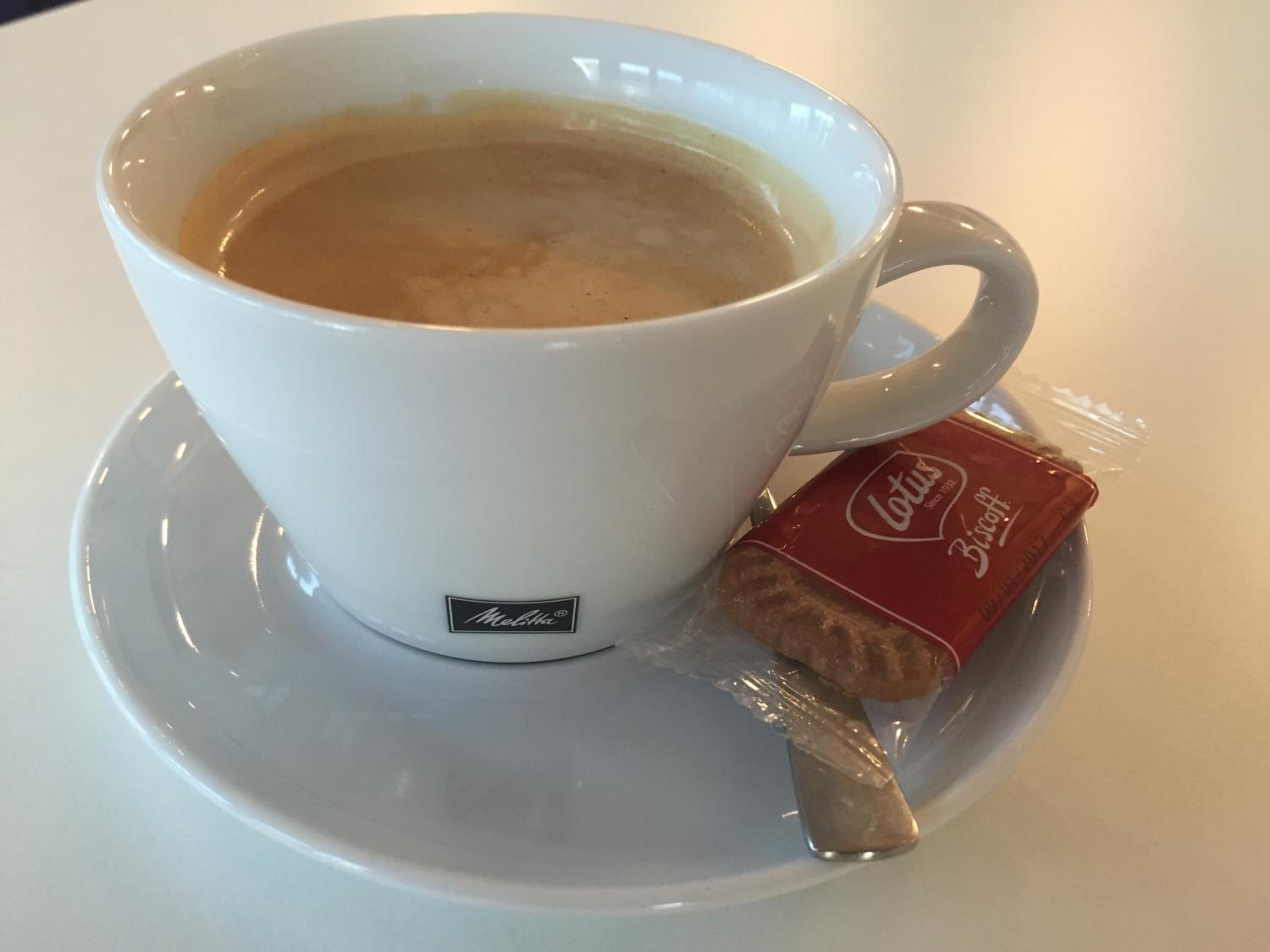 Une tasse de café blanc avec un sachet de thé posé sur une soucoupe.