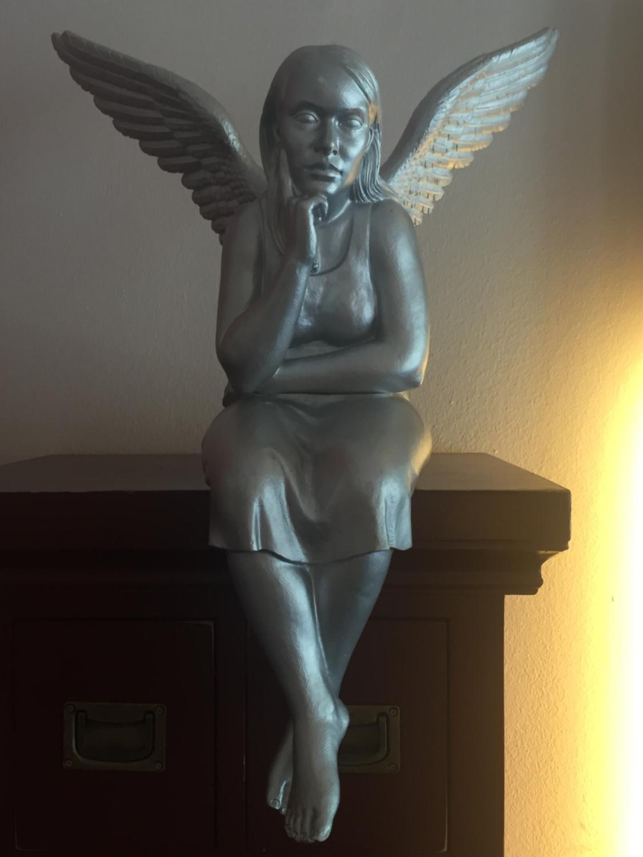 Una estatua de un ángel alado sentado sobre un pedestal.