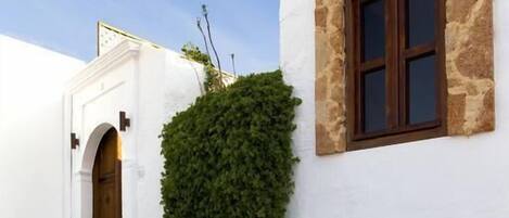 A white building with a stone window frame and a wooden door.
