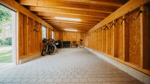 A covered bike storage area with wooden walls, a tiled floor, and bicycles parked inside. - Hirschenwirt (Eichstaett)