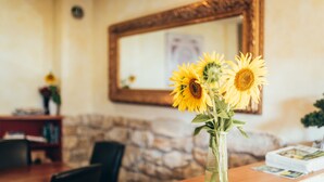 A wooden table with a vase of sunflowers, a stone wall, and a mirror on the wall. - Hirschenwirt (Eichstaett)