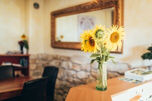 Una mesa de madera con un jarrón de girasoles, un muro de piedra y un espejo en la pared.