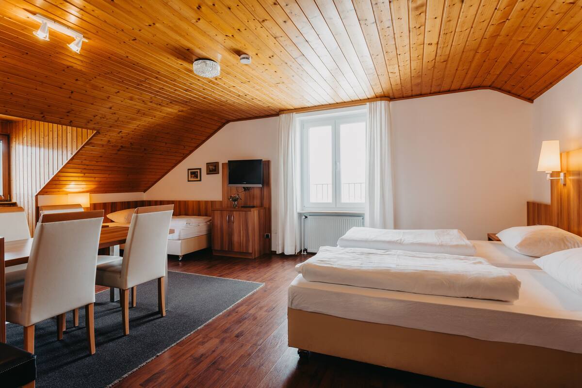 Un dormitorio con techos de madera, una cama, un escritorio y un televisor.
