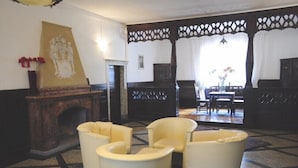 A room with a fireplace, a large painting, and a seating area with chairs. - Casagrande-Grosshaus (Laives)