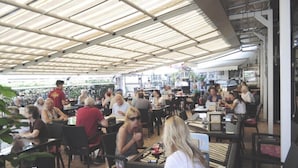 A crowded outdoor dining area with tables and chairs under a metal roof. - Casagrande-Grosshaus (Laives)