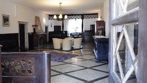A spacious lobby with a checkered floor, a chandelier, and a fireplace. - Casagrande-Grosshaus (Laives)