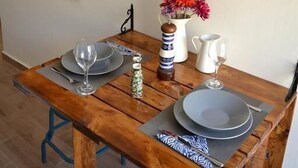 A wooden dining table with plates, glasses, and a vase of flowers. - CasaLindos Spitaki (Rhodes)
