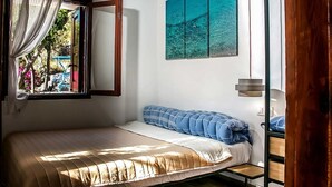 A bedroom with a bed, a window with curtains, a painting on the wall, and a bedside table. - CasaLindos Spitaki (Rhodes)