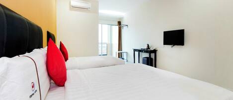 Quarto de hotel com duas camas, uma televisão de tela plana, uma mesinha com telefone e um aparelho de ar condicionado.