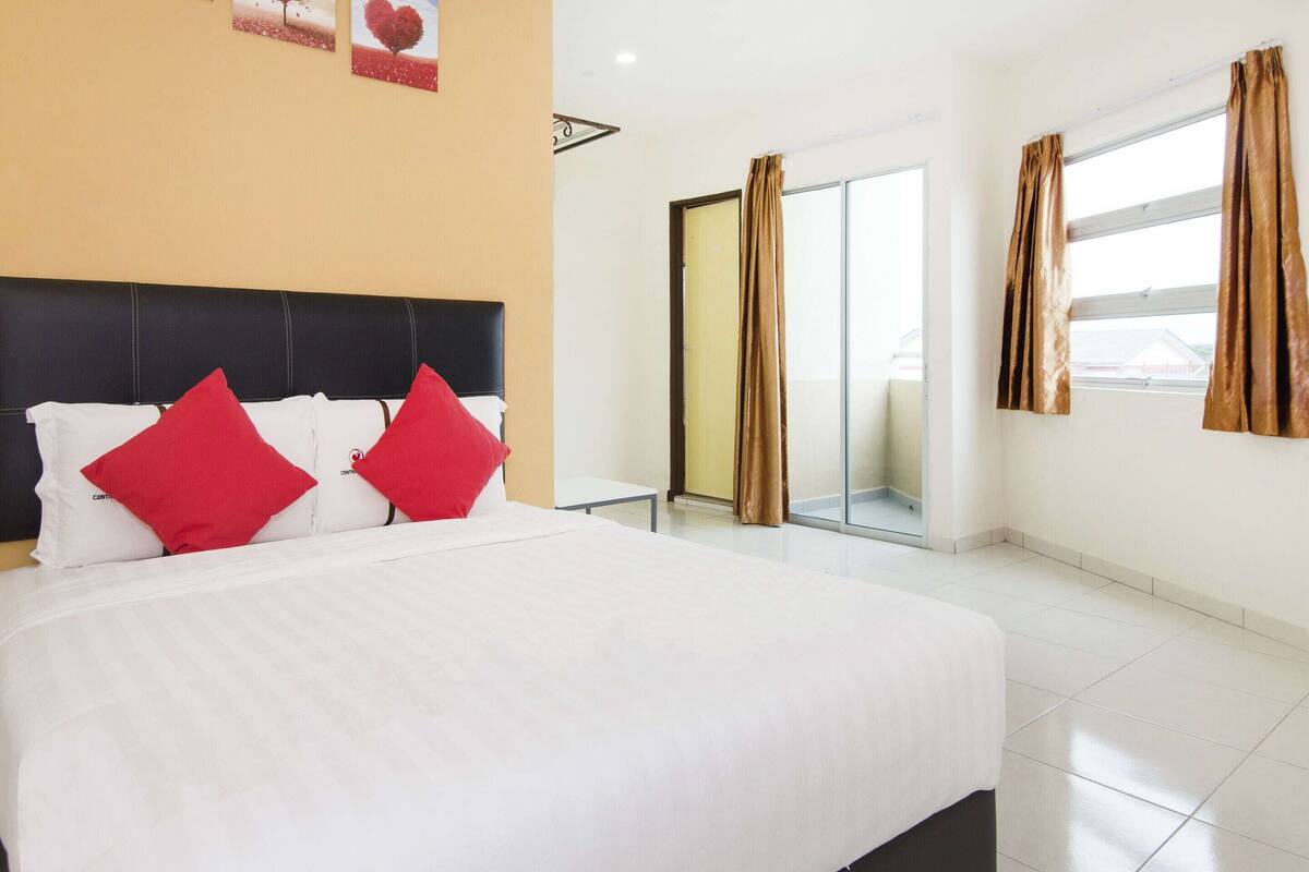 Habitación de hotel con una cama grande, una mesita pequeña, un ventanal corredero y vistas al exterior.