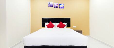 Una habitación de hotel moderna con una cama grande, un cabecero negro y una mesita de noche pequeña.