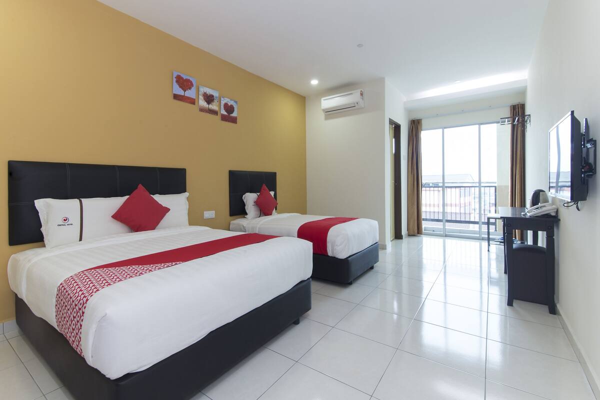 Habitación de hotel con dos camas, un escritorio, un televisor y un balcón con vistas.
