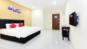 A hotel room with a large bed, a desk, a television, and three framed pictures on the wall.