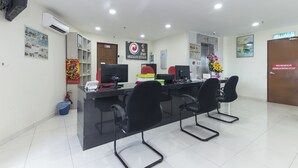A reception area with a reception desk, computers, and black chairs. There is a sign for the Central Hotel and a door labeled "KELUAR".