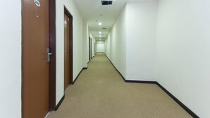 A long, narrow hotel corridor with carpeted floors and white walls.