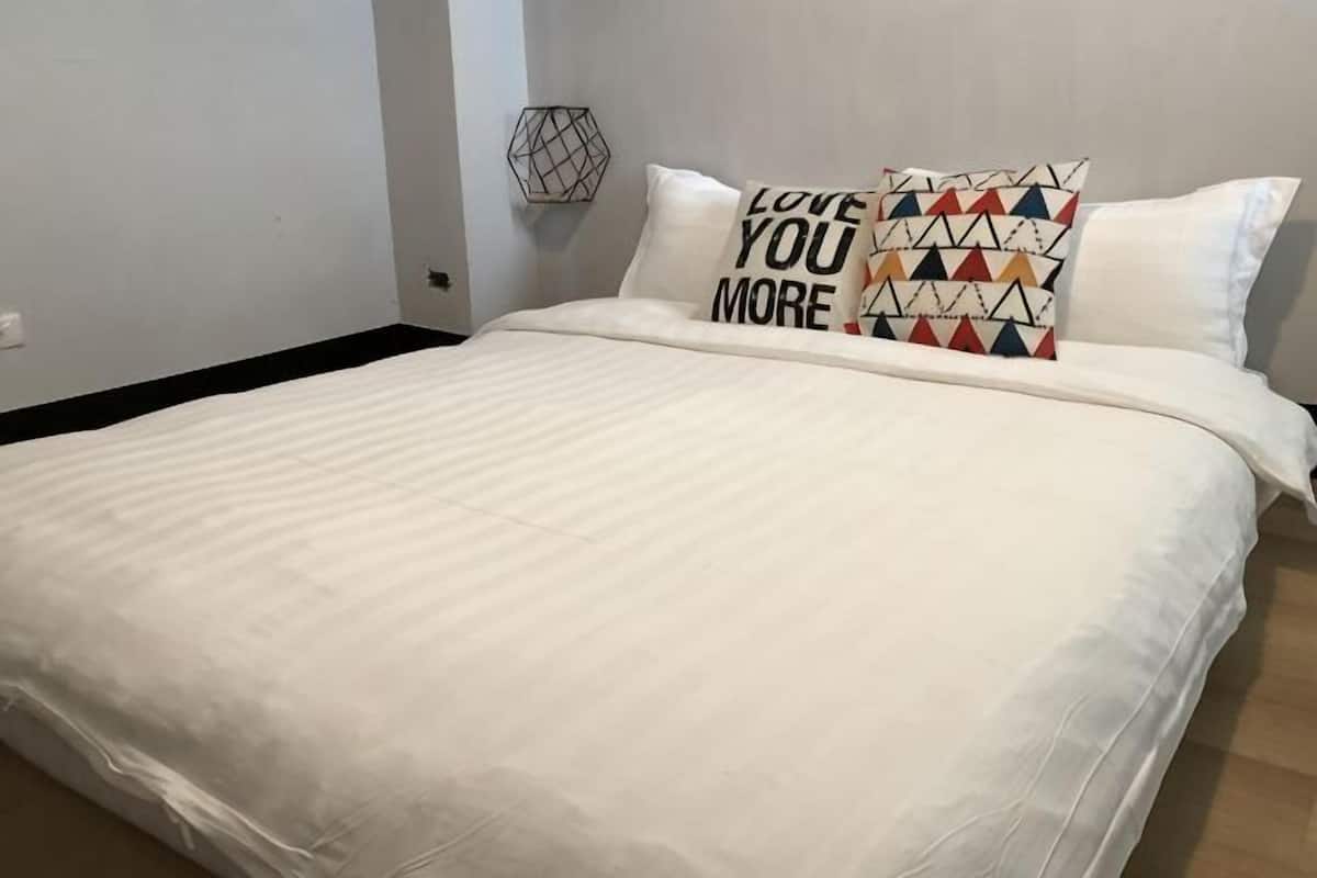Un lit bien fait, avec une literie blanche et deux coussins décoratifs.