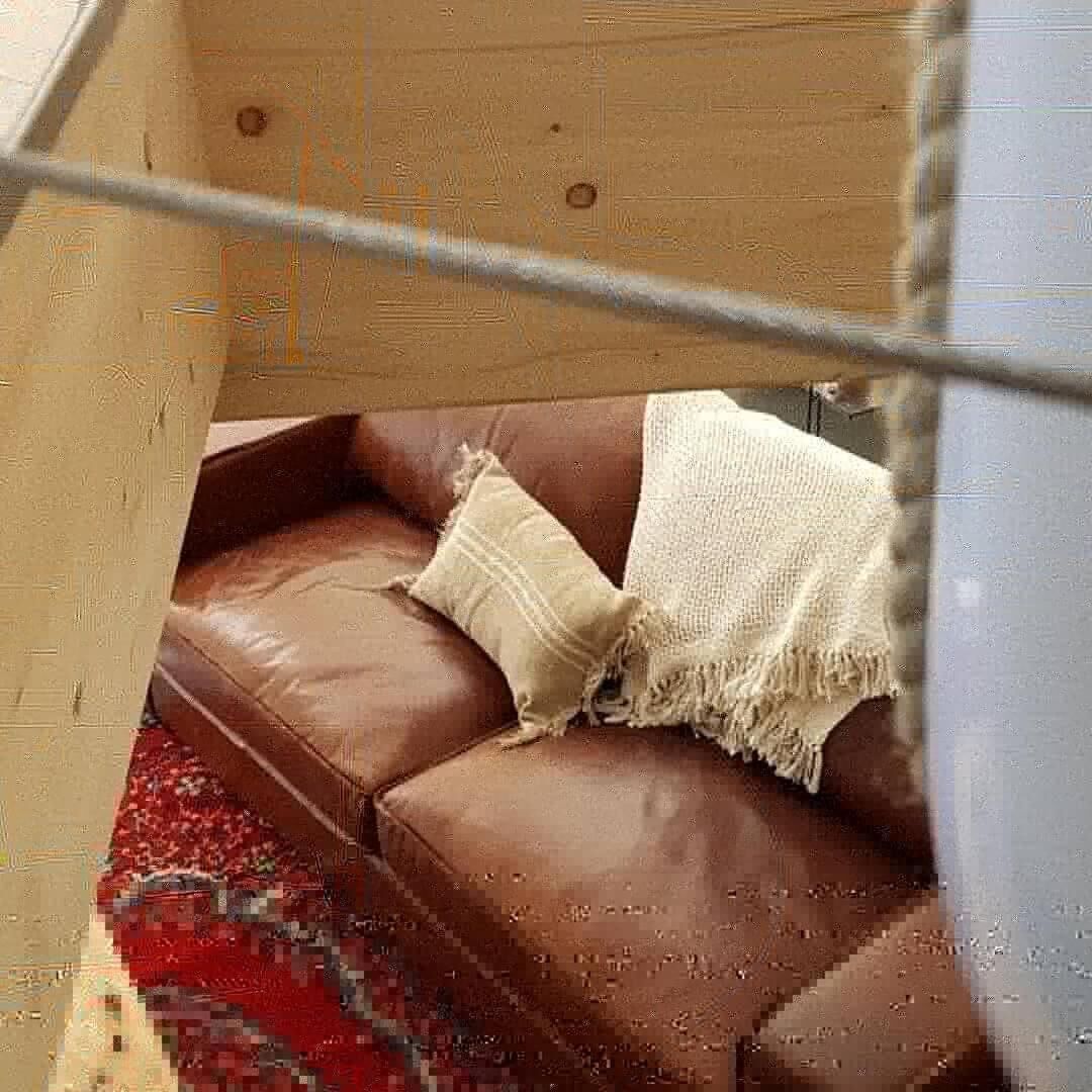 A brown leather sofa with a white throw blanket and a cushion.
