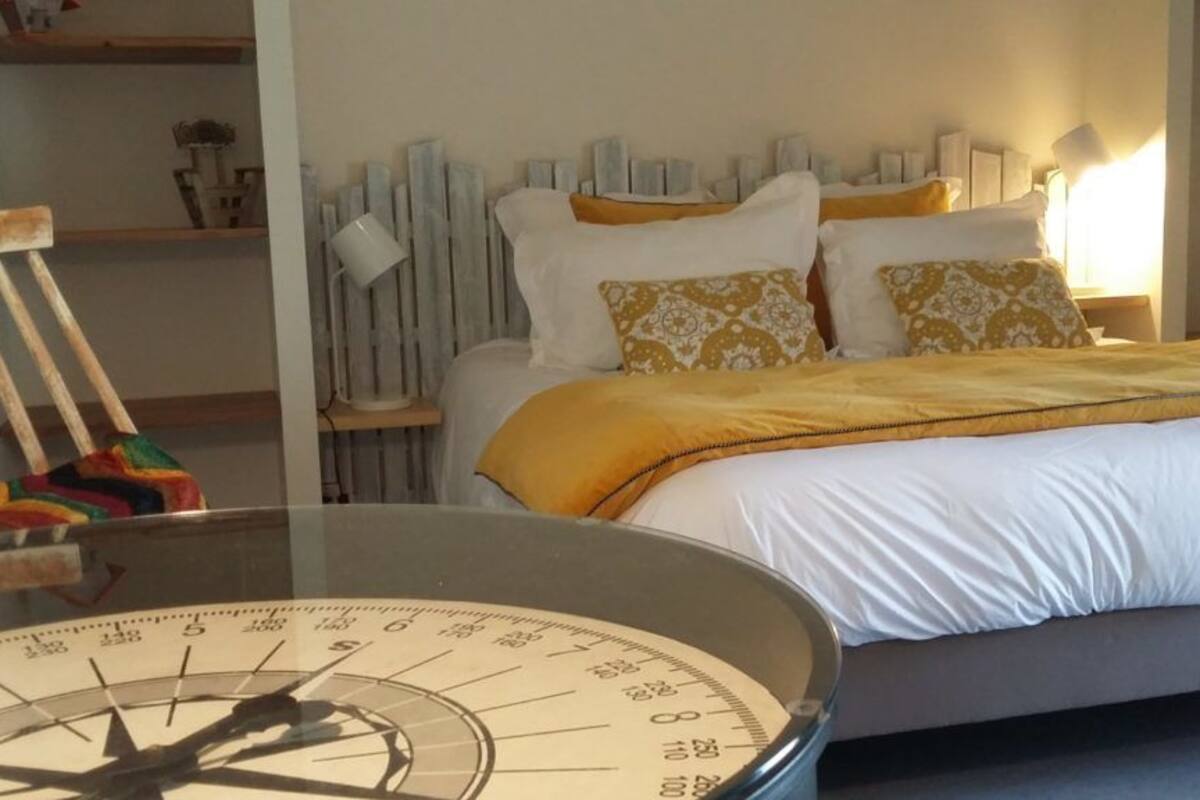 Ein Schlafzimmer mit einem Bett, einem Tisch mit Kompass und einem Regal mit Dekorationen.