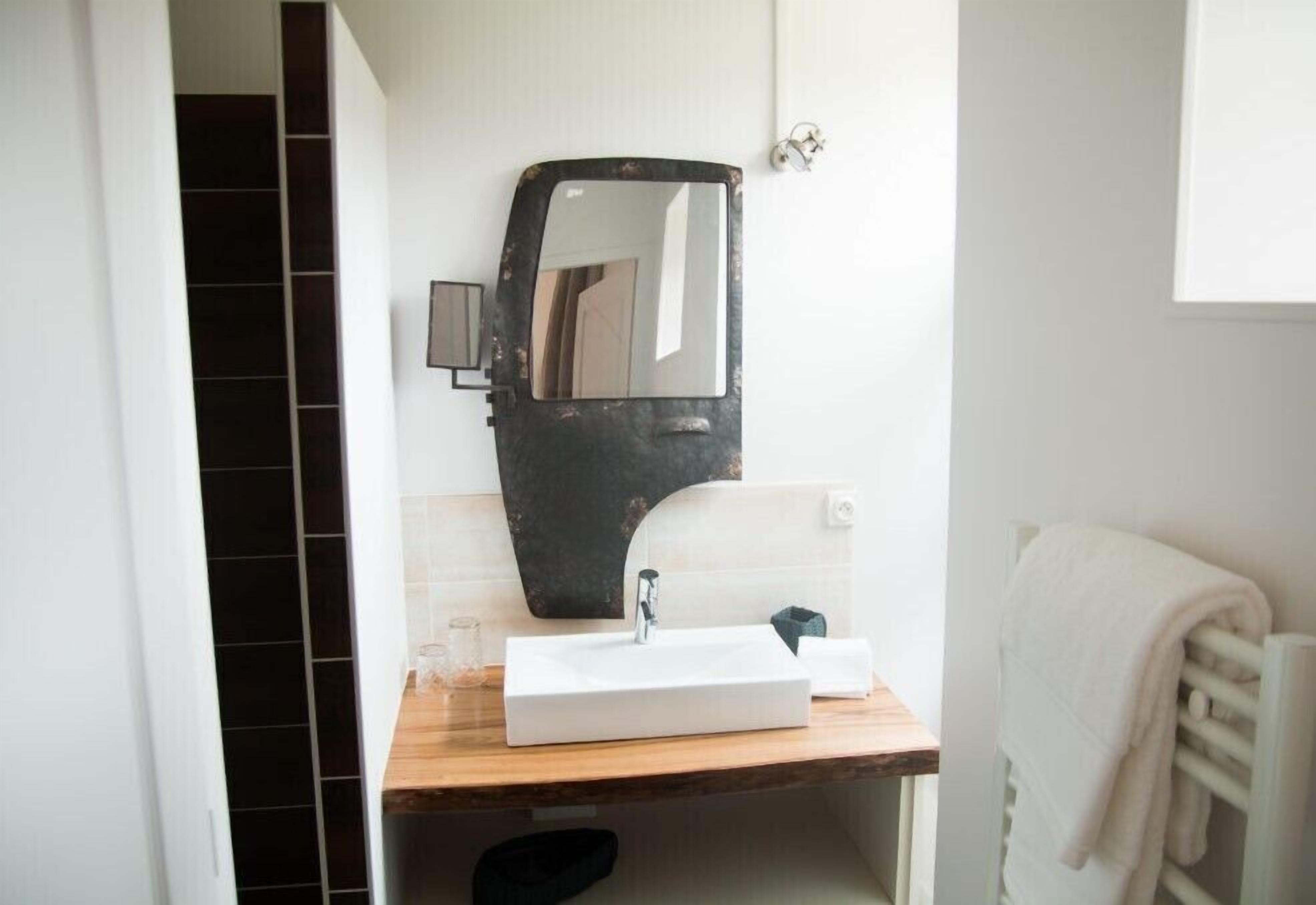 A bathroom with a white sink, a mirror, and a towel rack.