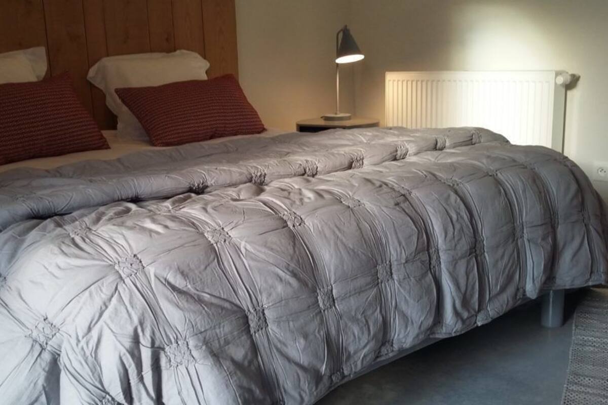 Ein Schlafzimmer mit einem großen Bett, einem Nachttisch mit Lampe und einer Heizung.