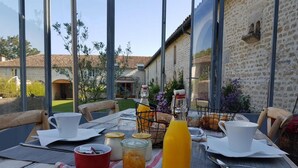 Mesa de comedor al aire libre con vista a un edificio rústico y follaje.