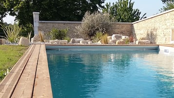 Una piscina al aire libre de temporada, sombrillas