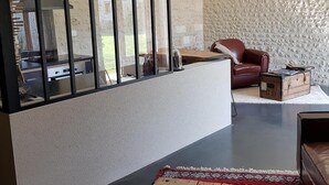 Un interior moderno con pared de piedra, sofá de cuero, mesa de madera y vistas a un espacio exterior.
