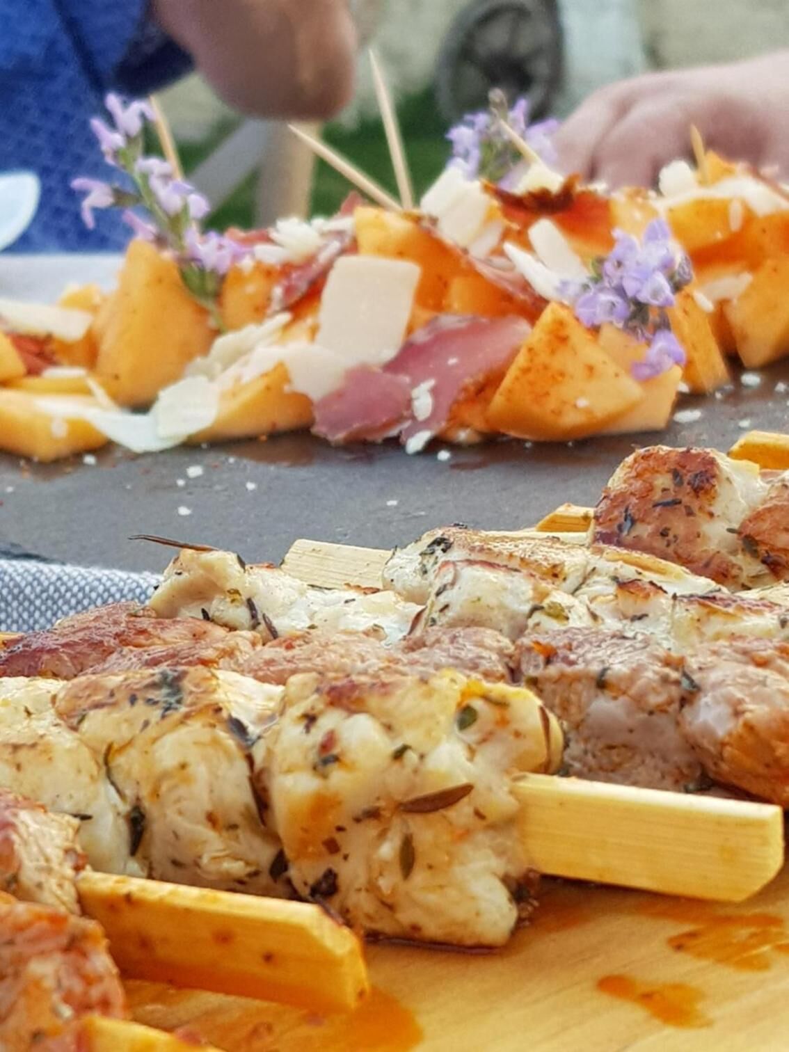 Diversos pinchos de comida sobre una tabla de madera, con trozos de carne y verduras.