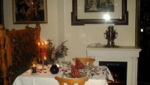 Comedor con chimenea, una mesa dispuesta para dos personas y un cuadro en la pared.