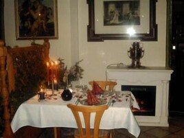 Uma sala de jantar com lareira, uma mesa posta para dois e um quadro na parede.