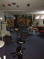 Uma academia com equipamentos de exercício, um espelho e um sofá vermelho.
