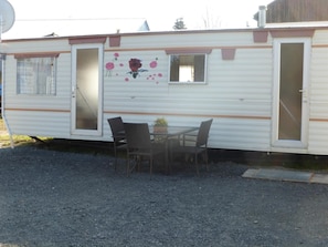 A mobile home with a dining area, a small table, and two chairs.