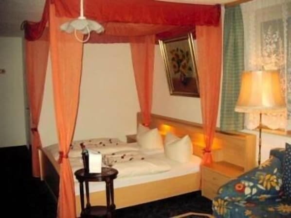A hotel room with a bed, a nightstand, a lamp, and a curtain.