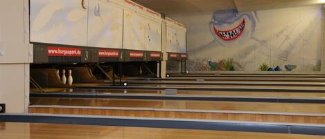 A bowling alley with lanes numbered 3 to 5 and a mural of a shark on the wall.
