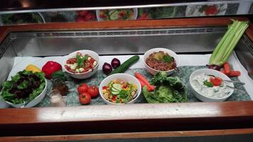 A variety of salads and vegetables displayed in a refrigerated section.