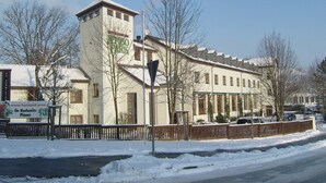 A building with a tower, a sign for 'Hotel Jembor Park', and a snow-covered street. - Jembo Park (Jena)
