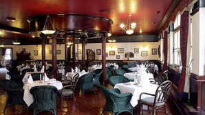 A restaurant with round tables, green wicker chairs, and a red ceiling. - Jembo Park (Jena)