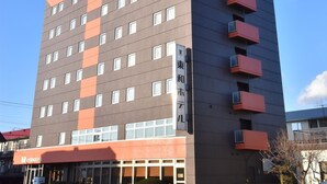 Un hotel de varios pisos con fachada plana, múltiples balcones y un cielo despejado al fondo.