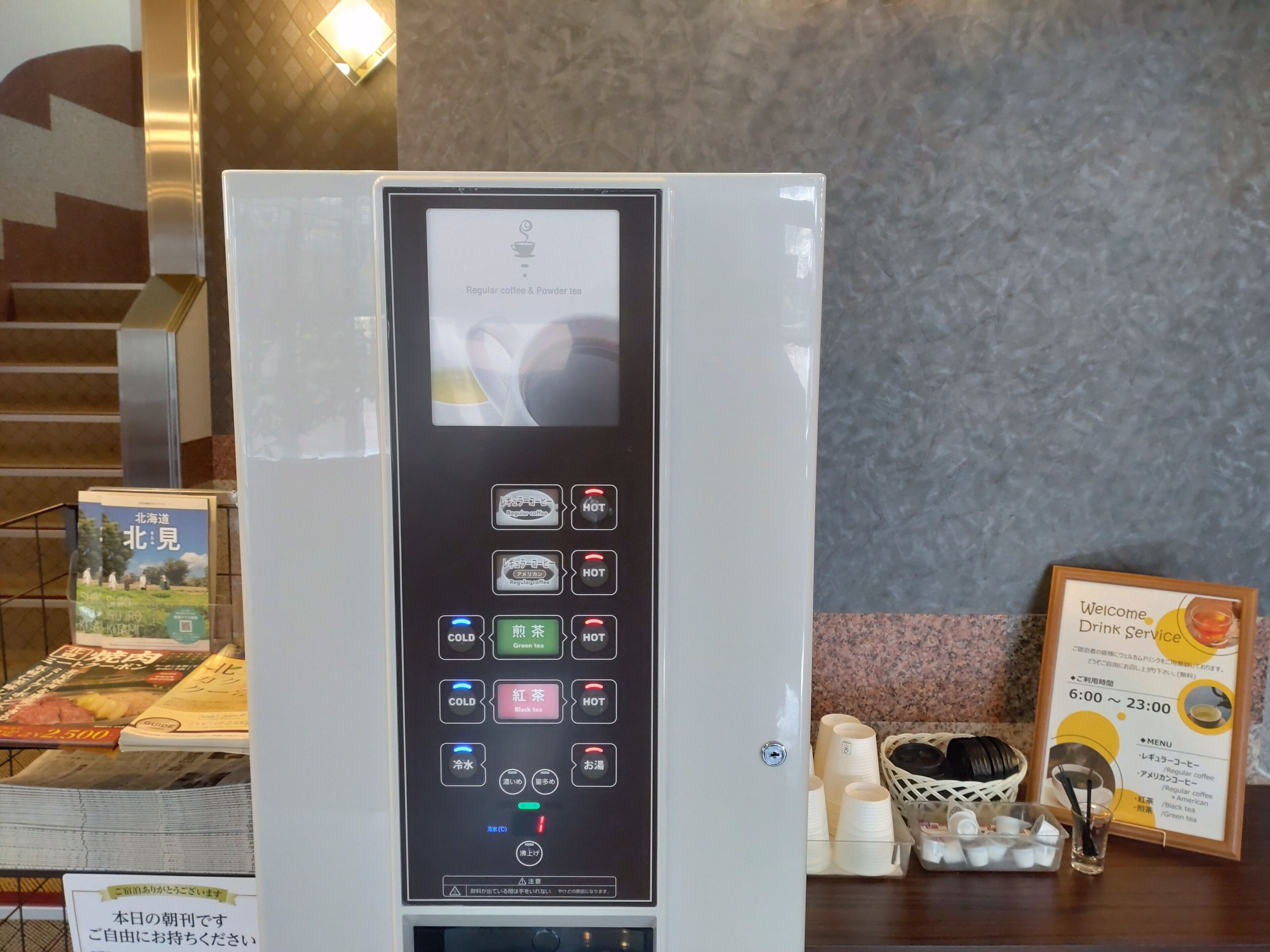 A coffee machine with various drink options and a sign indicating the drink service hours.