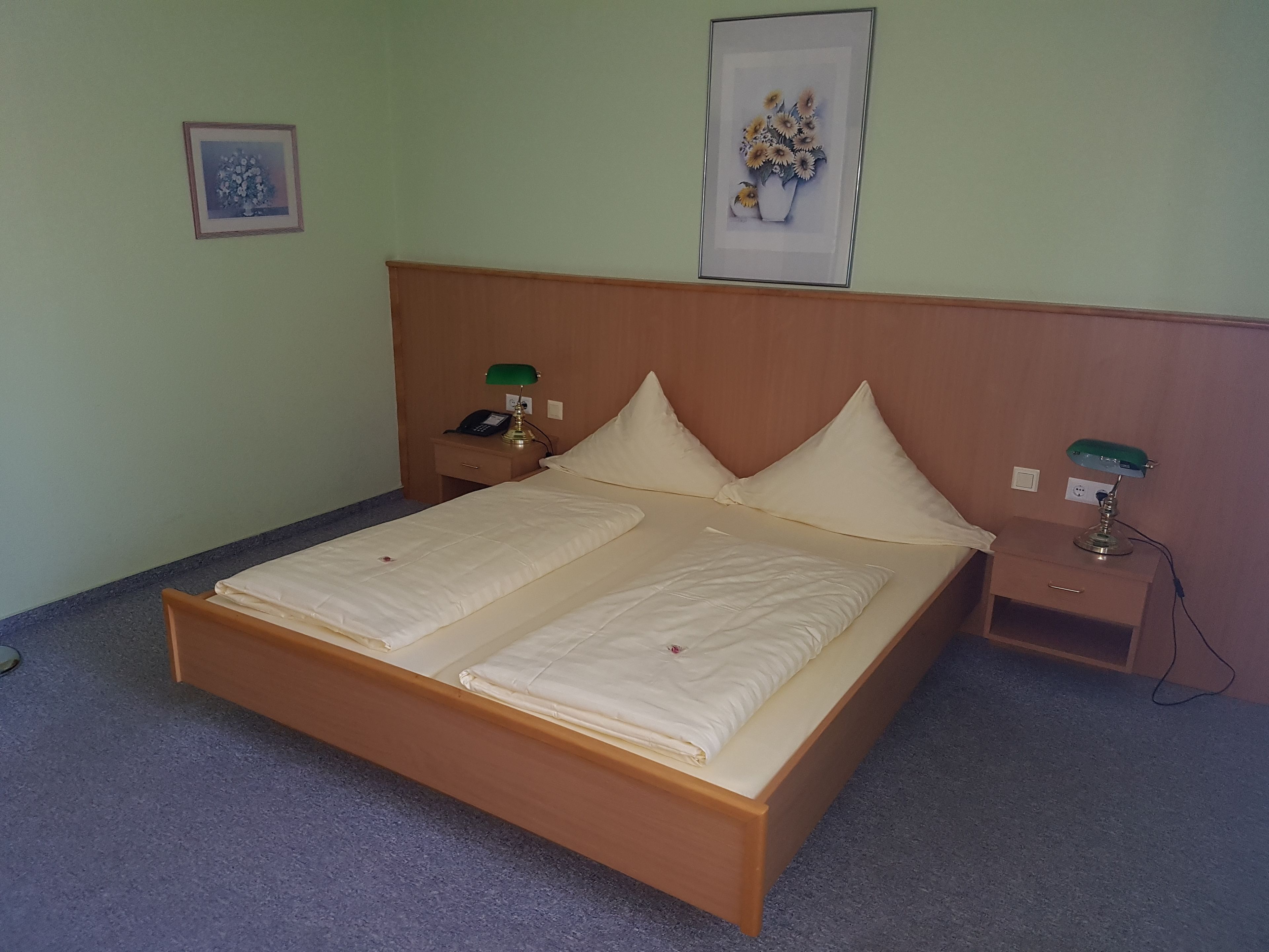 A single bed with a wooden frame, two bedside tables with lamps, and a wall-mounted telephone.