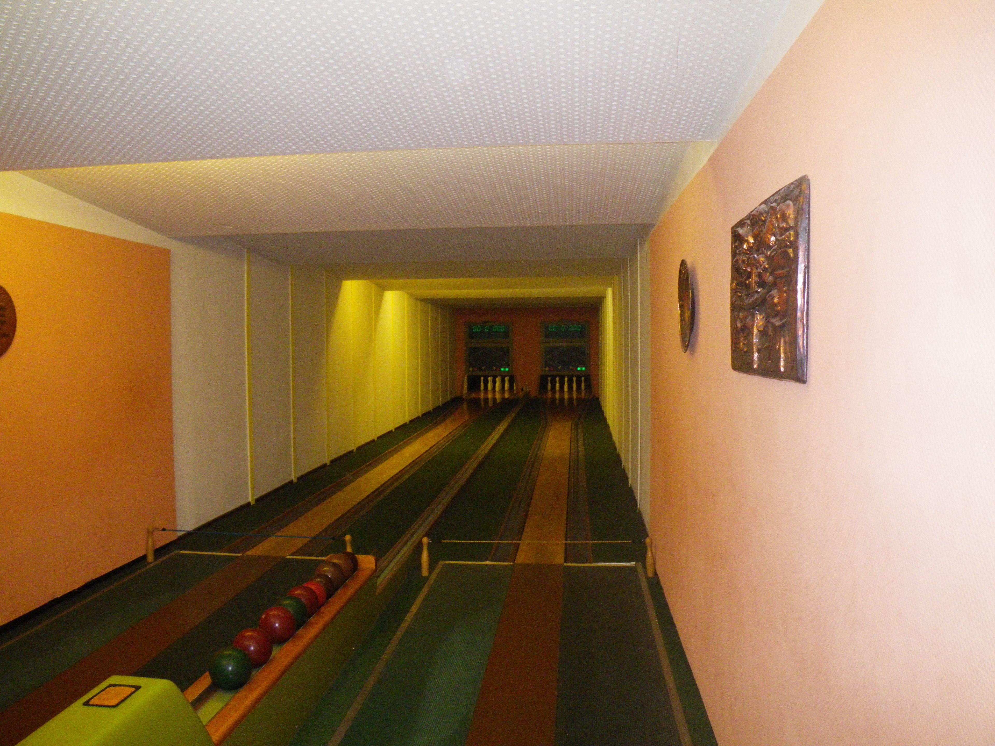 Bolera con pistas, bolos y piso cubierto de moqueta verde.