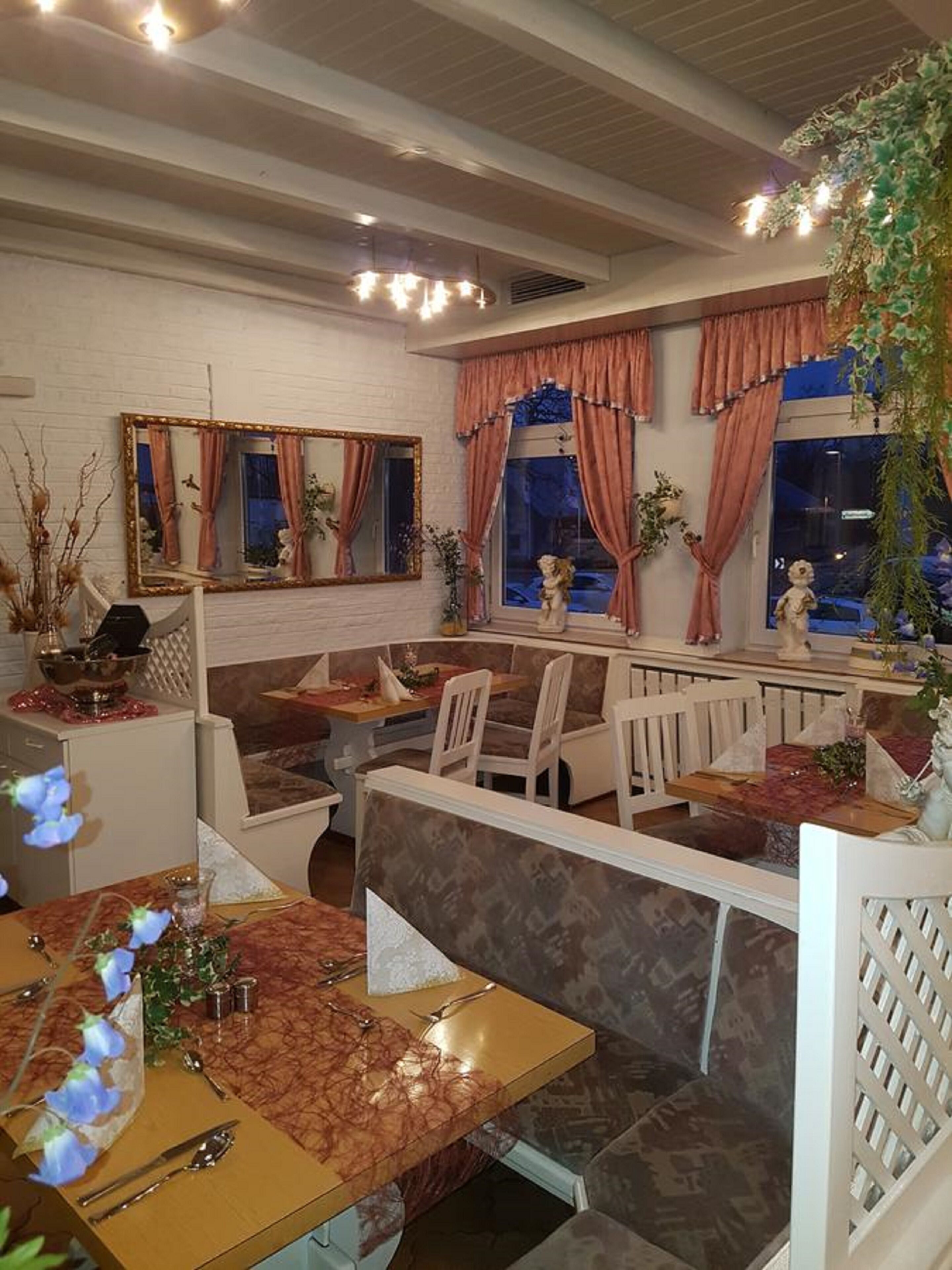 A restaurant with booths and tables, a white brick wall, and decorative plants.