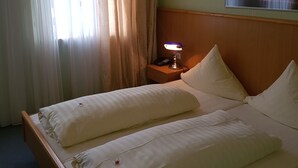 A hotel room with a bed, a nightstand with a lamp, and a painting on the wall. - Hotel Stadt Baunatal (Baunatal)