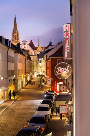 A cobblestone street lined with historic buildings, a prominent hotel sign, and a clock tower in the background. - Rosi Boutique Hotel (Regensburg)