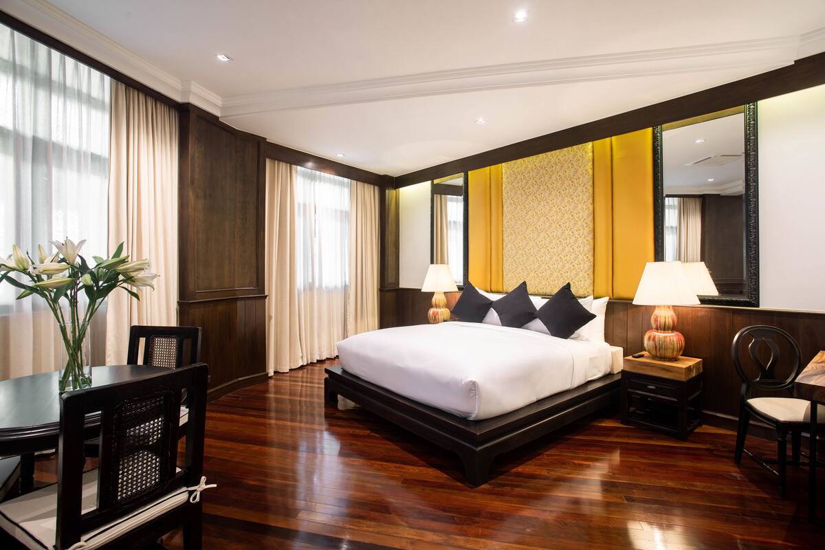 Een hotelkamer met een groot bed, een bureau, een stoel, een lamp en een spiegel.
