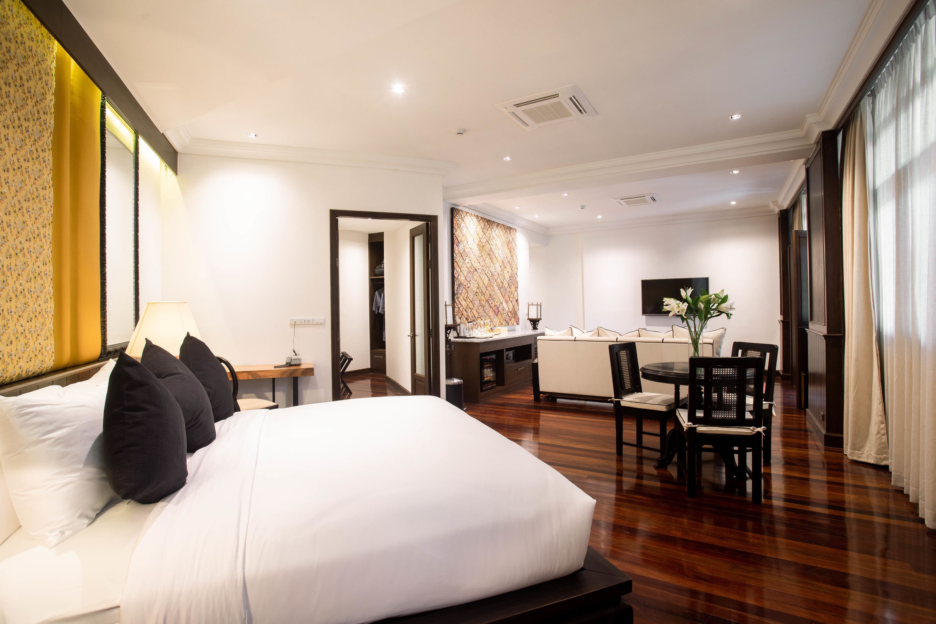 A hotel room with a large bed, a desk, a chair, and a small kitchenette.